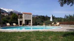 a swimming pool in a yard with chairs and an umbrella at Stratos Villas in Melidhónion