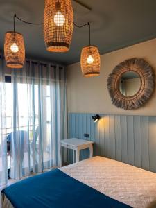 sypialnia z łóżkiem, 2 lampkami i lustrem w obiekcie Hôtel Les Alizés w mieście Cavalaire-sur-Mer