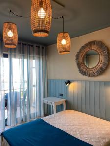 a bedroom with a bed and two lights and a mirror at H&ocirc;tel Les Aliz&eacute;s in Cavalaire-sur-Mer