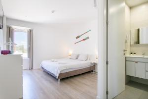 a white bedroom with a bed and a bathroom at Casa Amarela Guesthouse in Albufeira +105 photos