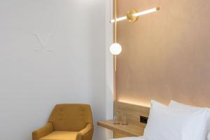 a bedroom with a chair and a bed and a lamp at Acropolis Magenta Luxury Suites in Athens