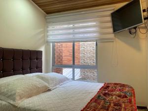 um quarto com uma cama e uma televisão de ecrã plano em Como en casa em Bogotá