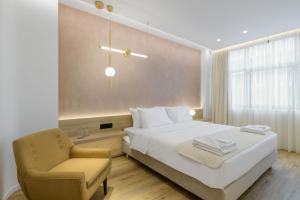 una camera con un letto bianco e una sedia di Acropolis Magenta Luxury Suites ad Atene