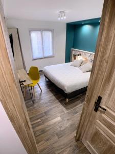 a bedroom with a bed and a table and a yellow chair at Eco-Appart'hôtel Rouen / SLT in Rouen