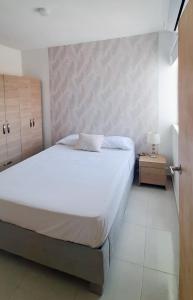 een slaapkamer met een groot wit bed en een nachtkastje bij Cómodo apartamento cerca al mar. in Cartagena