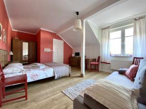 ウストカにあるSzary Domek Apartamenty Ustkaの赤い壁のベッドルーム1室、ベッド2台、デスクが備わります。