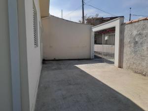 an empty alley with a white wall and a gate at Casa Agradável próxima ao Bosque in Pôrto Feliz