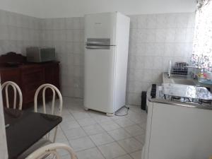 a kitchen with a refrigerator and a table and chairs at Casa Agradável próxima ao Bosque in Pôrto Feliz