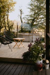 a wooden deck with a table and chairs and flowers at Na miły Bug Guesthouse by Bug river 