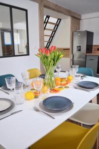 Eco-Appart'hôtel Rouen / SLT في رووين: طاولة بيضاء مع لوحات زرقاء وزهور في مزهرية