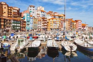 een groep boten aangemeerd in een haven met gebouwen bij Apartamento Noray Bermeo in Bermeo