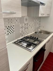 uma cozinha branca com um fogão e um lavatório em Nuovo bilocale a 150 mt dal mare em Porto Torres