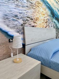um quarto com uma cama e uma mesa com um candeeiro em Nuovo bilocale a 150 mt dal mare em Porto Torres