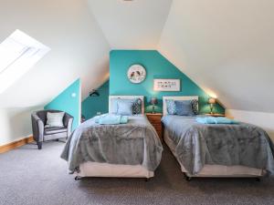 a attic bedroom with two beds and a chair at Barcud Cottage in Carmarthen