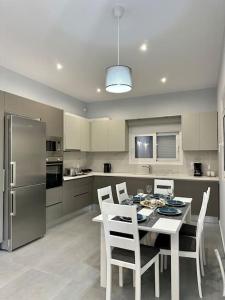a kitchen with a table with chairs and a refrigerator at Zouf House Luxury Stay with Jacuzzi in Panayía Mesosporítissa