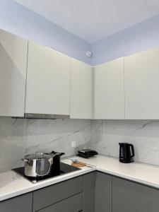 una cocina con armarios blancos y una olla en una estufa en Zouf house en Panayía Mesosporítissa