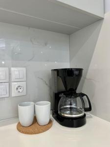una cafetera y dos tazas en un mostrador en Zouf house en Panayía Mesosporítissa