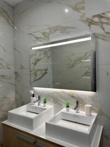 uma casa de banho branca com 2 lavatórios e um espelho em Zouf house em Panayía Mesosporítissa