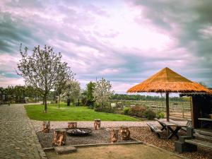 a picnic table and a straw umbrella in a park at De Worfthoeve in Geel