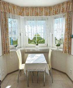 comedor con mesa, sillas y ventanas en Homestay Sweet Island, en Gager