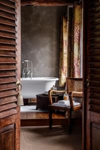 a bathroom with a bath tub and a chair at La Magnanerie de Seillans in Seillans
