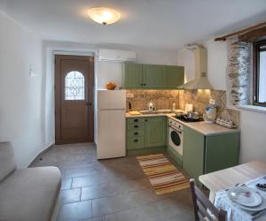 a kitchen with green cabinets and a white refrigerator at Feneri 3 -Cozy rustic Apt 20' from Elafonisi beach in Perivólia