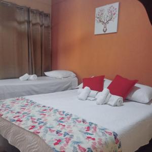 una camera con due letti con cuscini rossi e bianchi di El Cocobolo Food&Rest Room 4 Bed and Breakfast WiFi AC Pkg gratis a Liberia