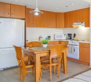 a kitchen with a table and chairs and a white refrigerator at The Whale Suite @Waikiki Banyan (1 Free Parking) in Honolulu
