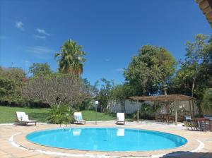 a swimming pool with two lounge chairs and a table at Pousada Rio de Contas in Rio de Contas