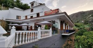 a white building with umbrellas in front of it at Casa Rural La Yedra San Mateo in Arbejales