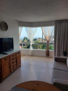 托雷莫利諾斯的住宿－Lovely apartment in Torremolinos Views of the sea, pool, terrace, sofa bed and fully equipped kitchen，一间带电视和大窗户的客厅