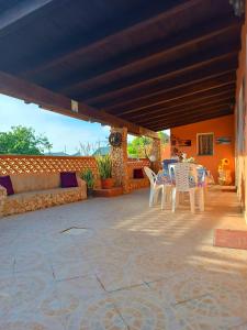 un patio con sillas blancas y una mesa. en A due passi da Cala Pisana, en Lampedusa