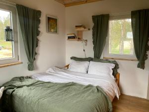 a bed in a bedroom with two windows at Różana Zagroda Agroturystyka in Osiek