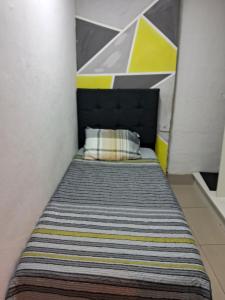 Cama en habitación pequeña con pared amarilla y gris en Minha casa sua casa completa, en Guarulhos