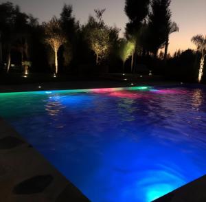 einen Pool mit blauen und grünen Lichtern in der Unterkunft Villa de Ferme Wafaa - Location de Rêve avec Piscine près de Mazagan in El Jadida