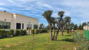 ein Haus mit Bäumen vor einem Hof in der Unterkunft Villa de Ferme Wafaa - Location de Rêve avec Piscine près de Mazagan in El Jadida