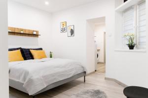 een slaapkamer met witte muren en een bed met oranje kussens bij The Central Border Premium Apartment in Štúrovo
