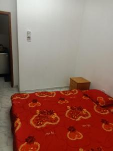 Una cama roja con un edredón rojo con flores. en Private room for upto 4 peope, en Sharjah