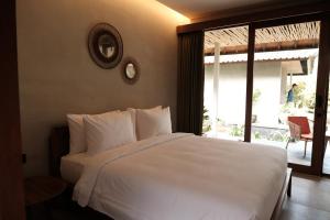 um quarto com uma cama branca e uma grande janela em Cloudspace Ubud em Ubud