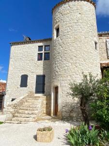 um grande edifício de pedra com uma torre com escadas em Maison de village, charme et confort em Mauroux