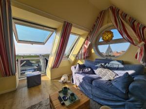 ein Wohnzimmer mit einem blauen Sofa und einem Fenster in der Unterkunft Ferienwohnung Inselblick Norddeich mit Meerblick in Norden