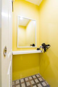 Baño amarillo con espejo y estante en Matchbox Bangkok Hostel, en Bangkok