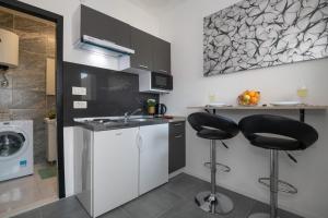 eine Küche mit einem Waschbecken und 2 Barhockern in der Unterkunft Apartment Viktorija in Dubrovnik + 8 Fotos