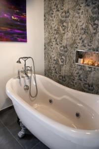 een wit bad in een badkamer met een schilderij bij Boutique Hotel Ferrara in Ferrara