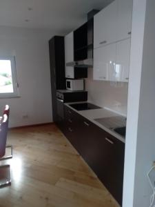 een keuken met zwart-witte kasten en een houten vloer bij Apartmani Binka in Petrcane