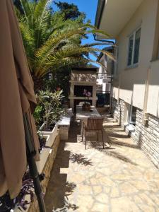 een patio met een open haard en een tafel en stoelen bij Apartmani Binka in Petrcane