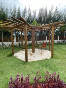 a wooden pergola with a bench in a yard at Itacimirim Summer Ville - Pé na Areia in Itacimirim