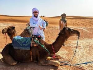 a man sitting on a camel in the desert at Sahara wild camping in Mhamid