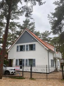 a white house with a fence and trees at Villa PortoBianco in Pobierowo