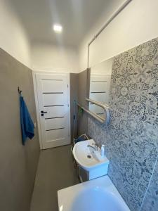La salle de bains est pourvue d'un lavabo blanc et d'une porte. dans l'établissement Quiet and peaceful apartment close to the city center, à Riga